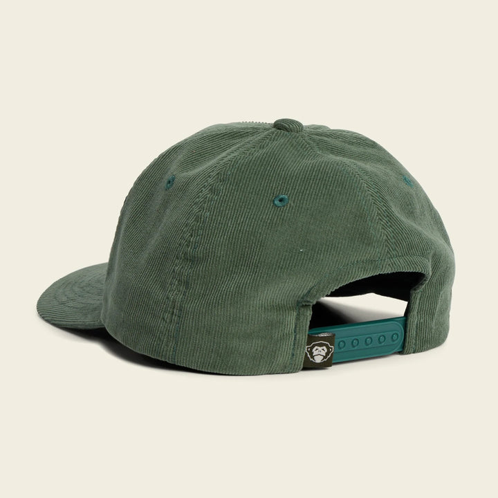 Green cap with a Howler Brothers brand logo on the back against a beige background