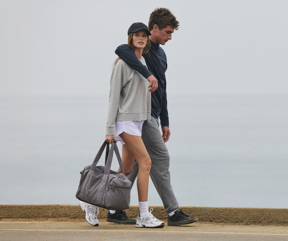 a man and a woman walking in vuori clothing with a bag