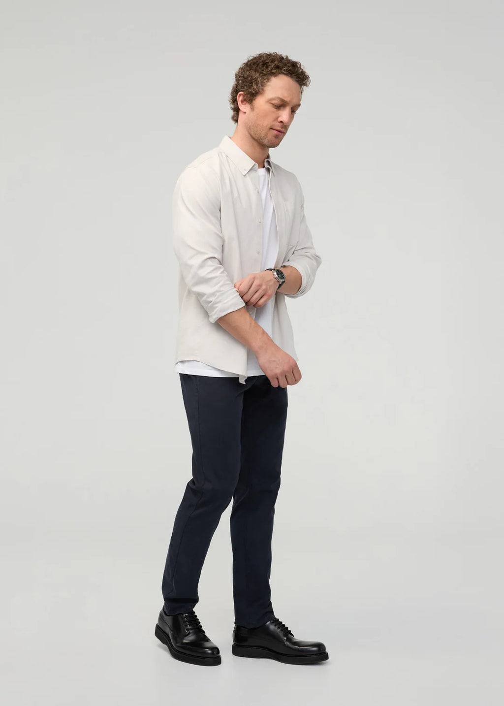 Man wearing a light-colored shirt and dark pants on a plain background