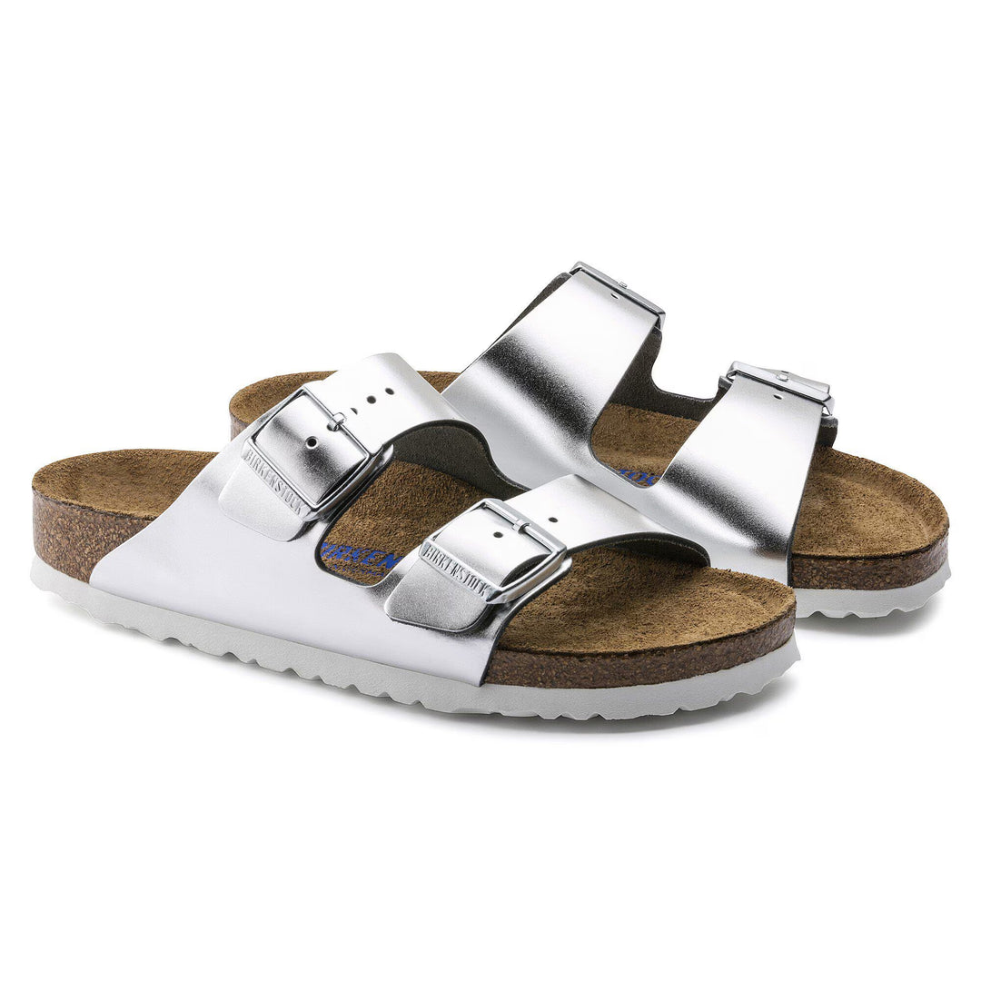 Silver sandals with brown soles on a white background