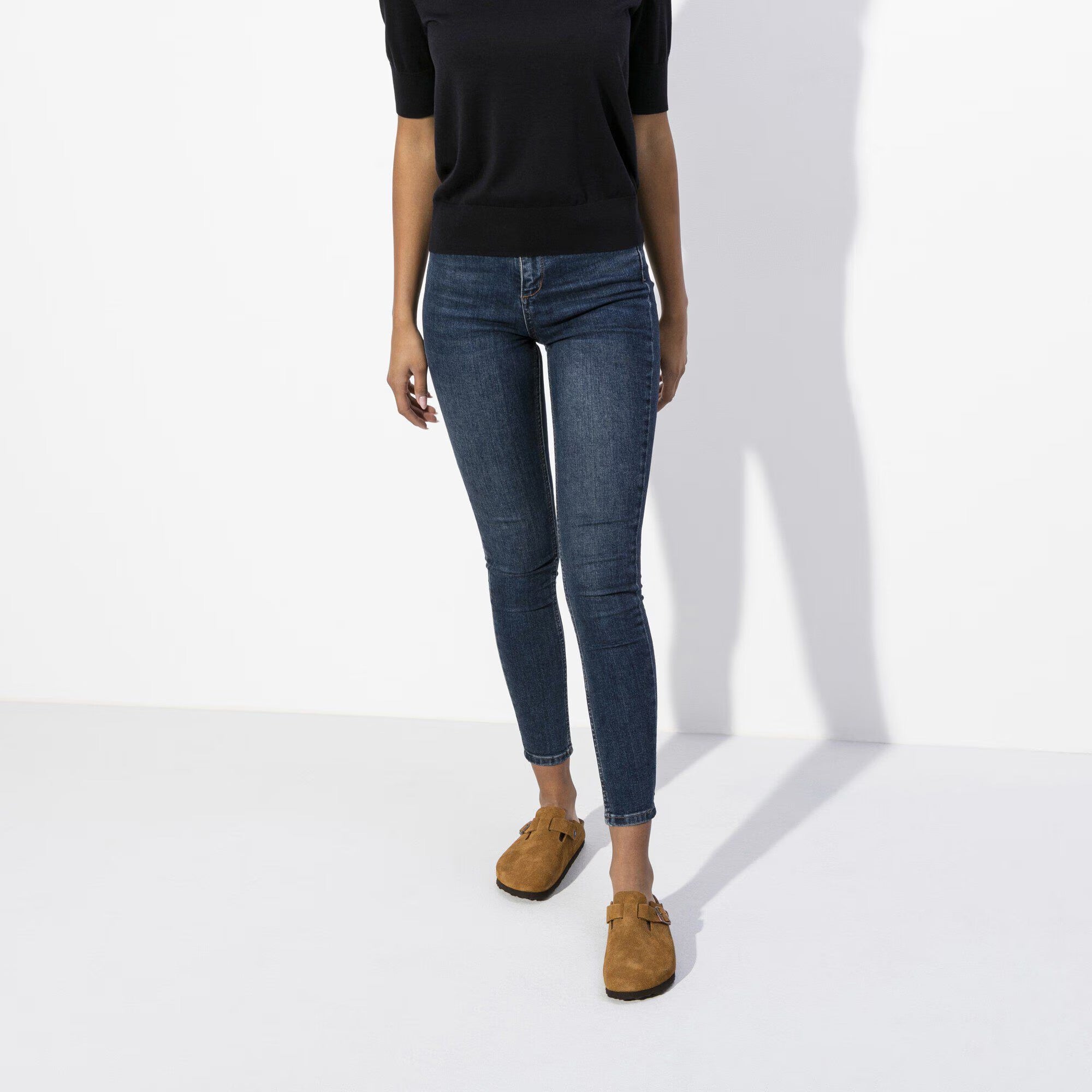 Pair of Brown suede clogs with a buckle on a white background worn by a model