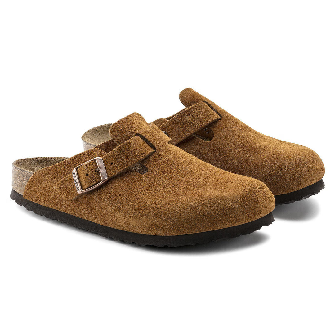 Pair of brown suede clogs with a buckle on a white background