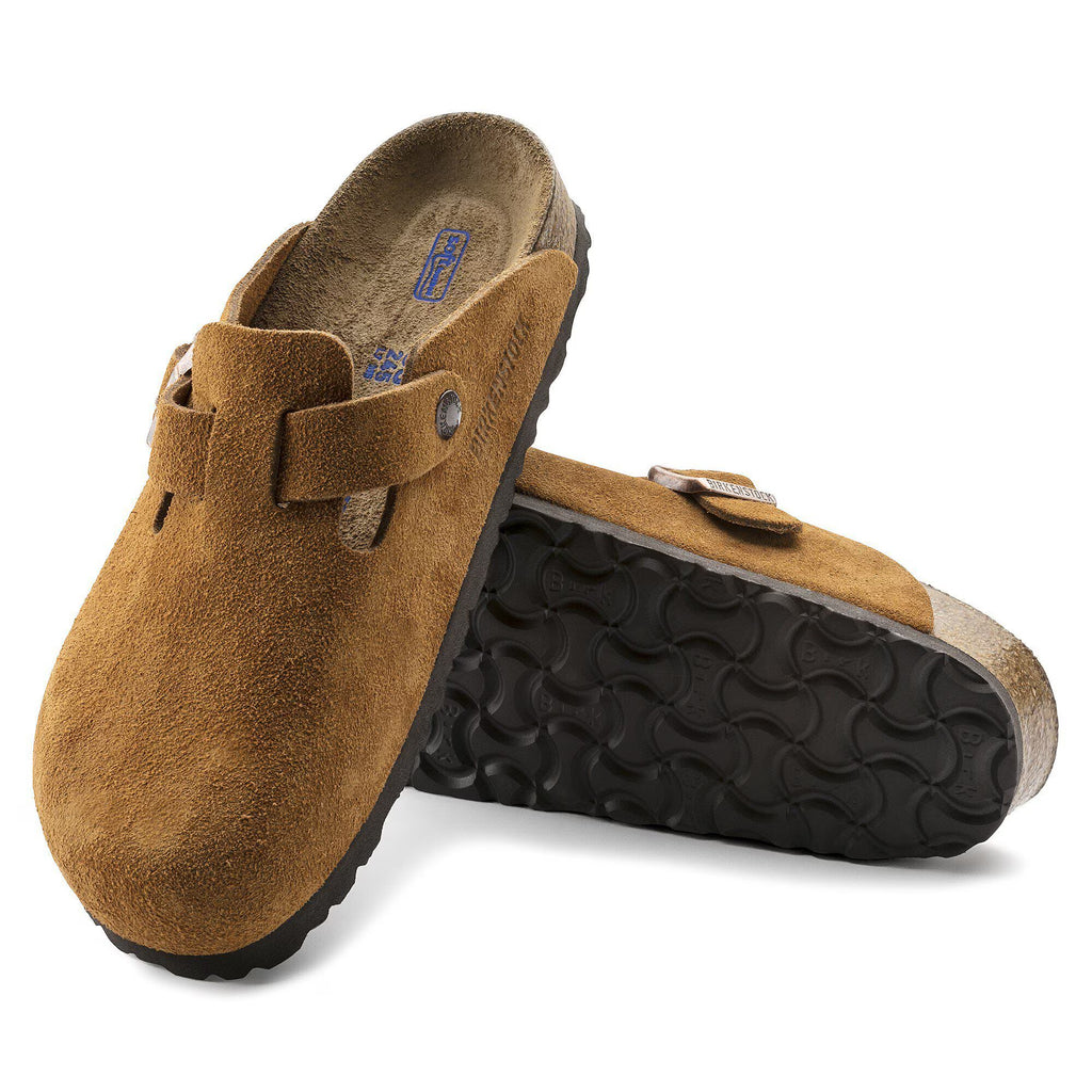 Pair of Brown suede clogs with a buckle on a white background