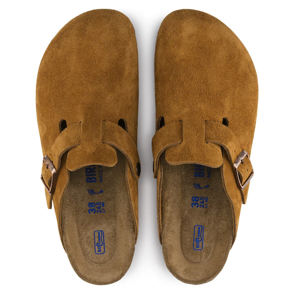 Pair of Brown suede clogs with a buckle on a white background