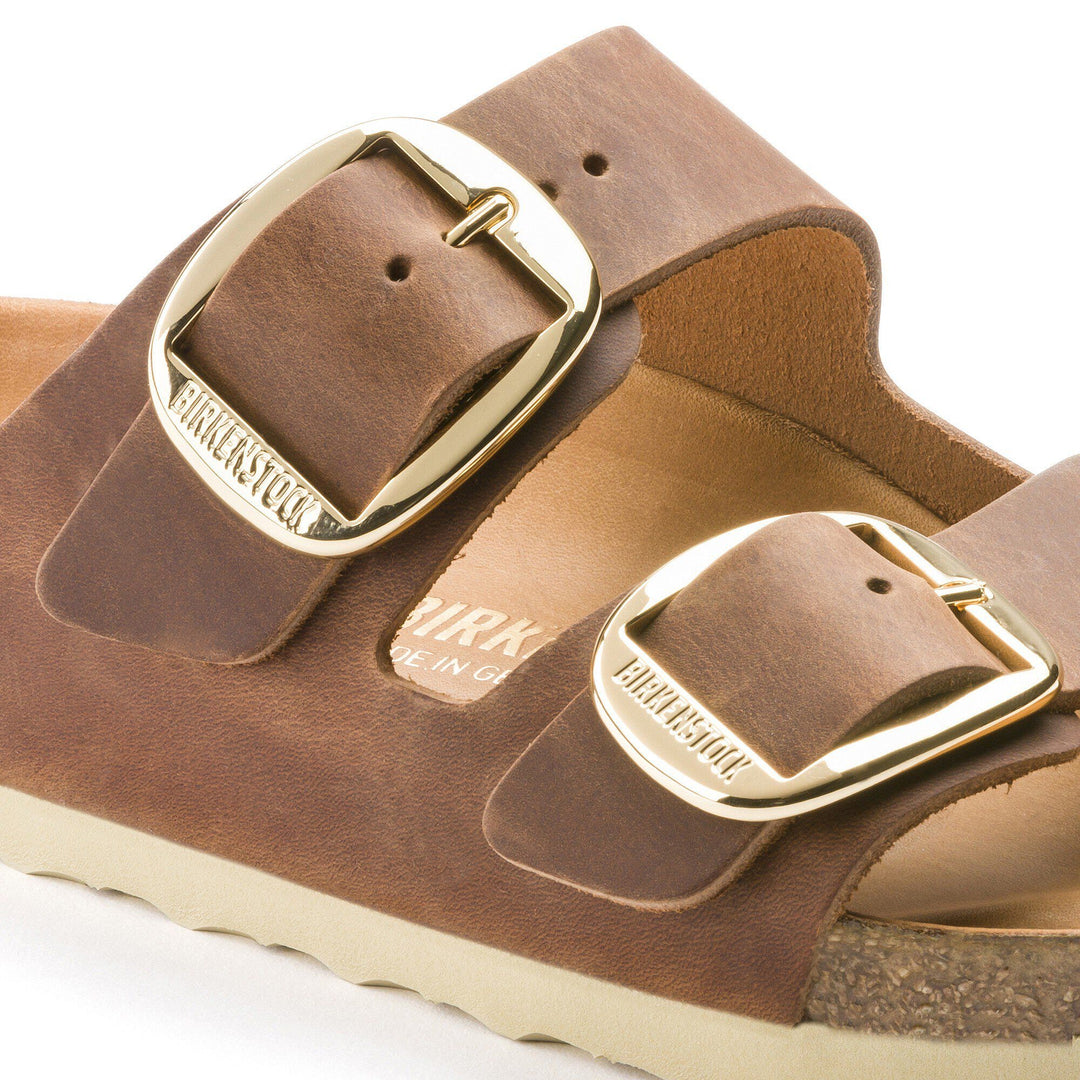 Brown leather sandals with gold buckles on a white background