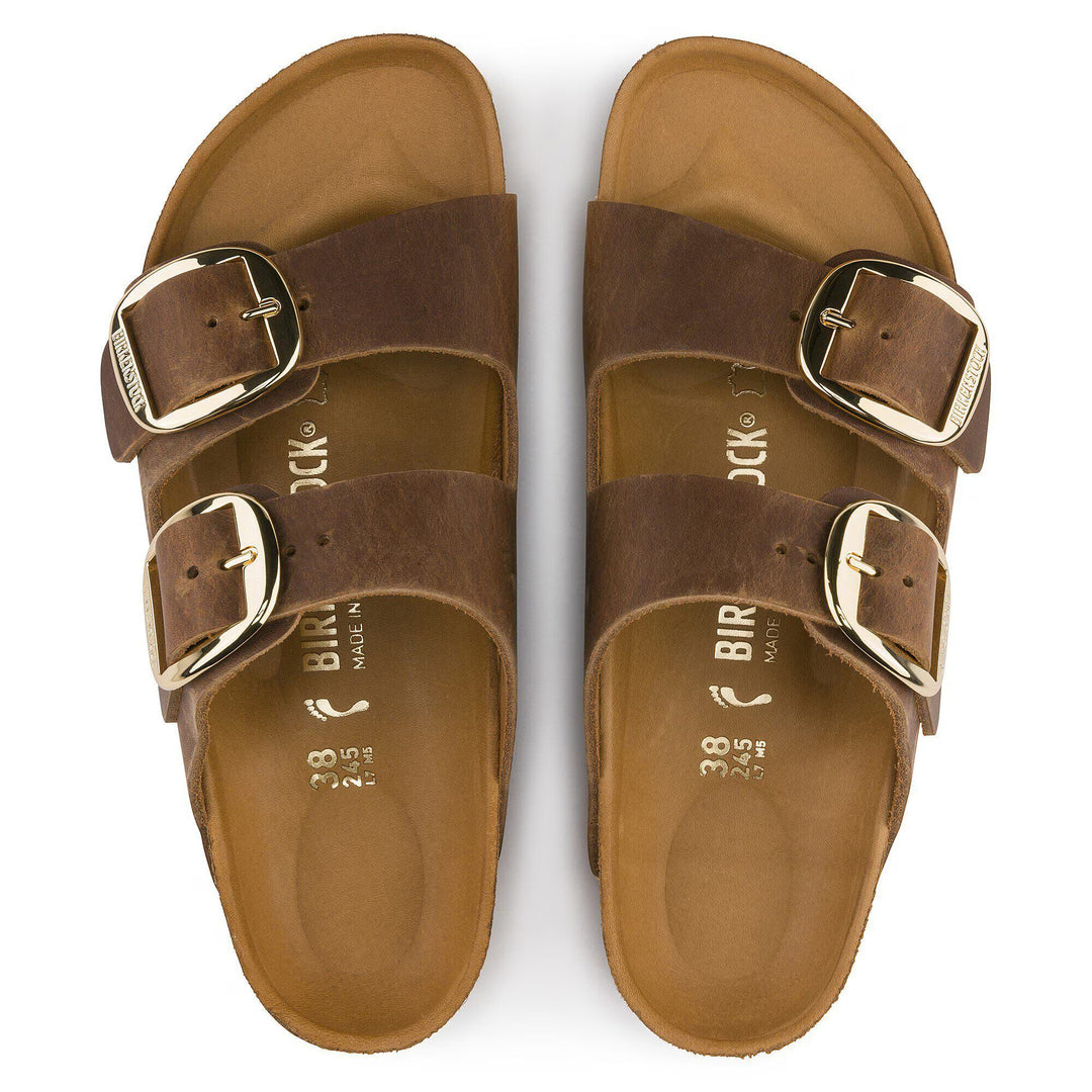 Pair of brown Birkenstock sandals with gold buckles on a white background