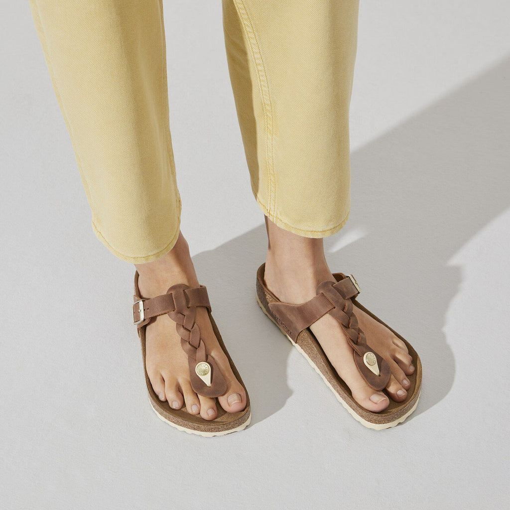 Brown sandals worn with yellow pants on a light gray background