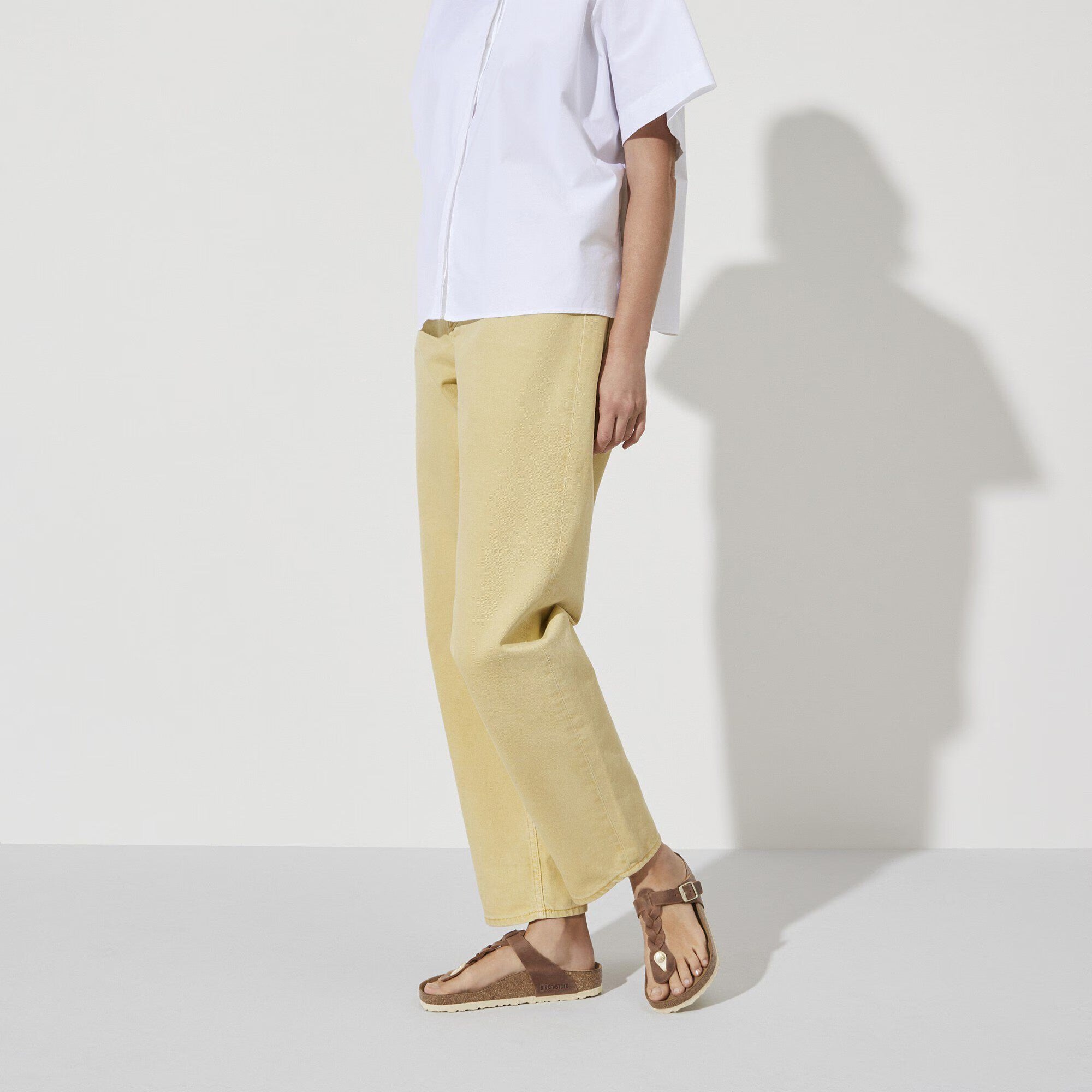 Person wearing a white shirt and beige pants on a plain background
