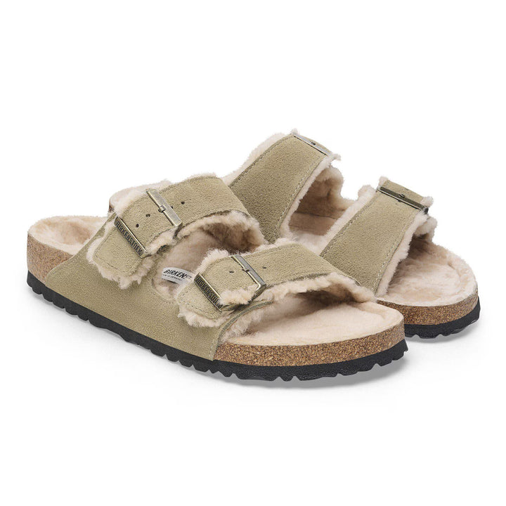 Pair of green sandals with shearling lining on a white background