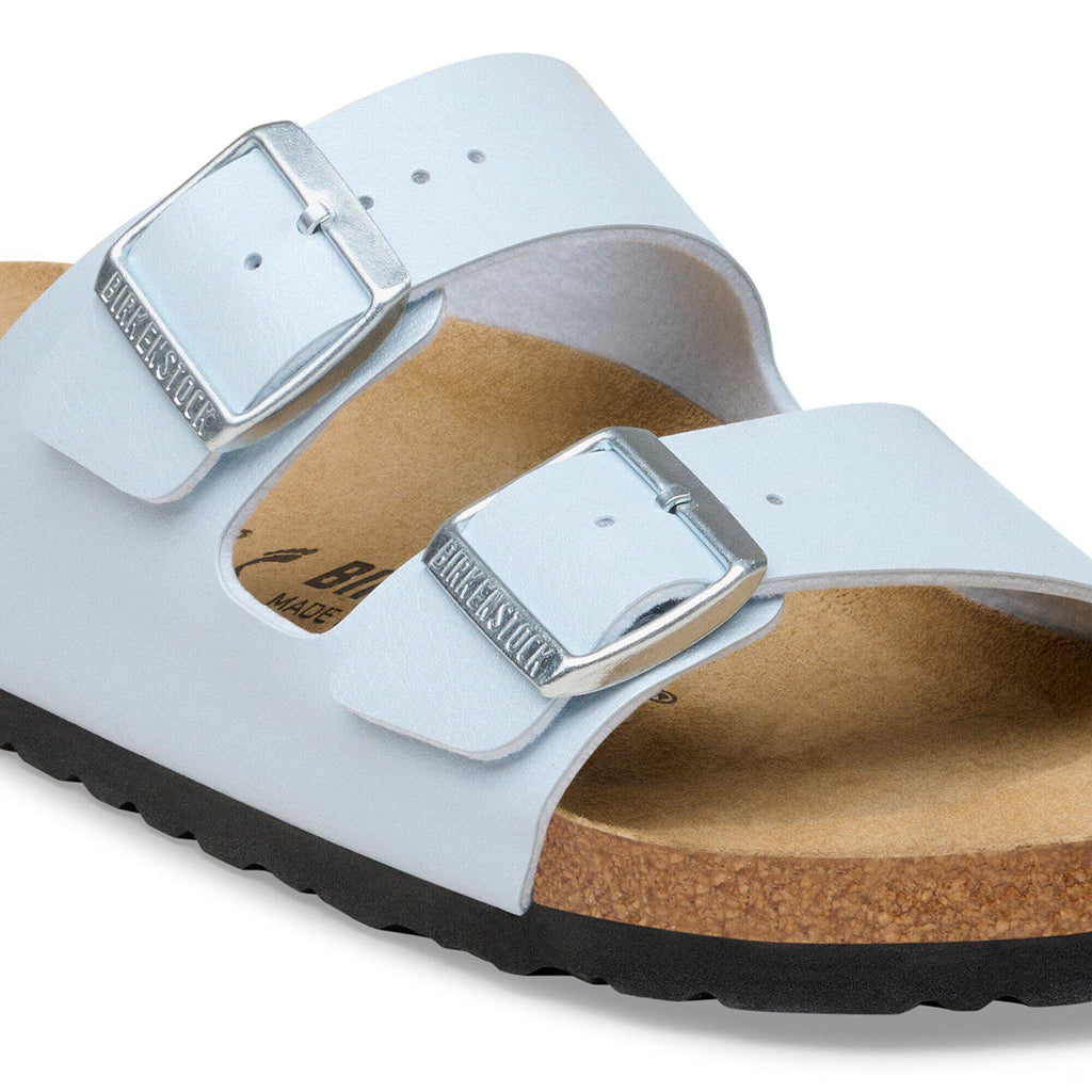 White sandal with metallic buckle on a white background