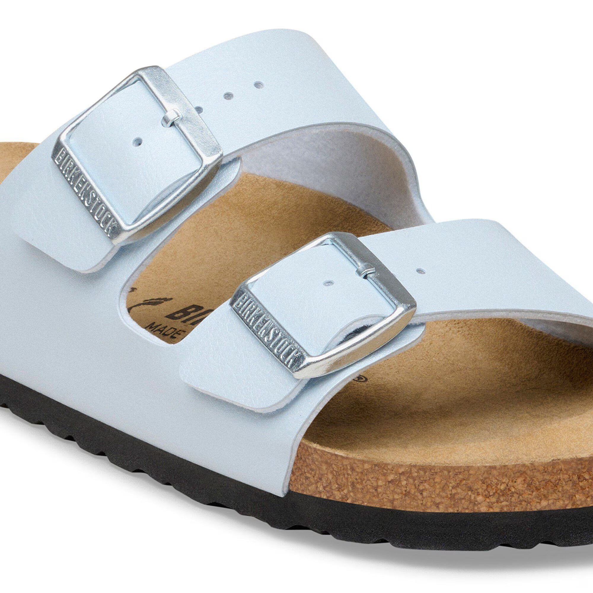 White sandal with metallic buckle on a white background