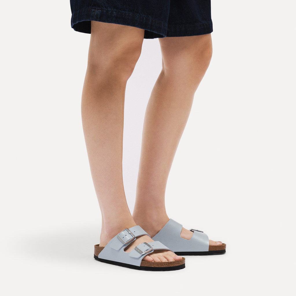 Person wearing light blue sandals on a white background