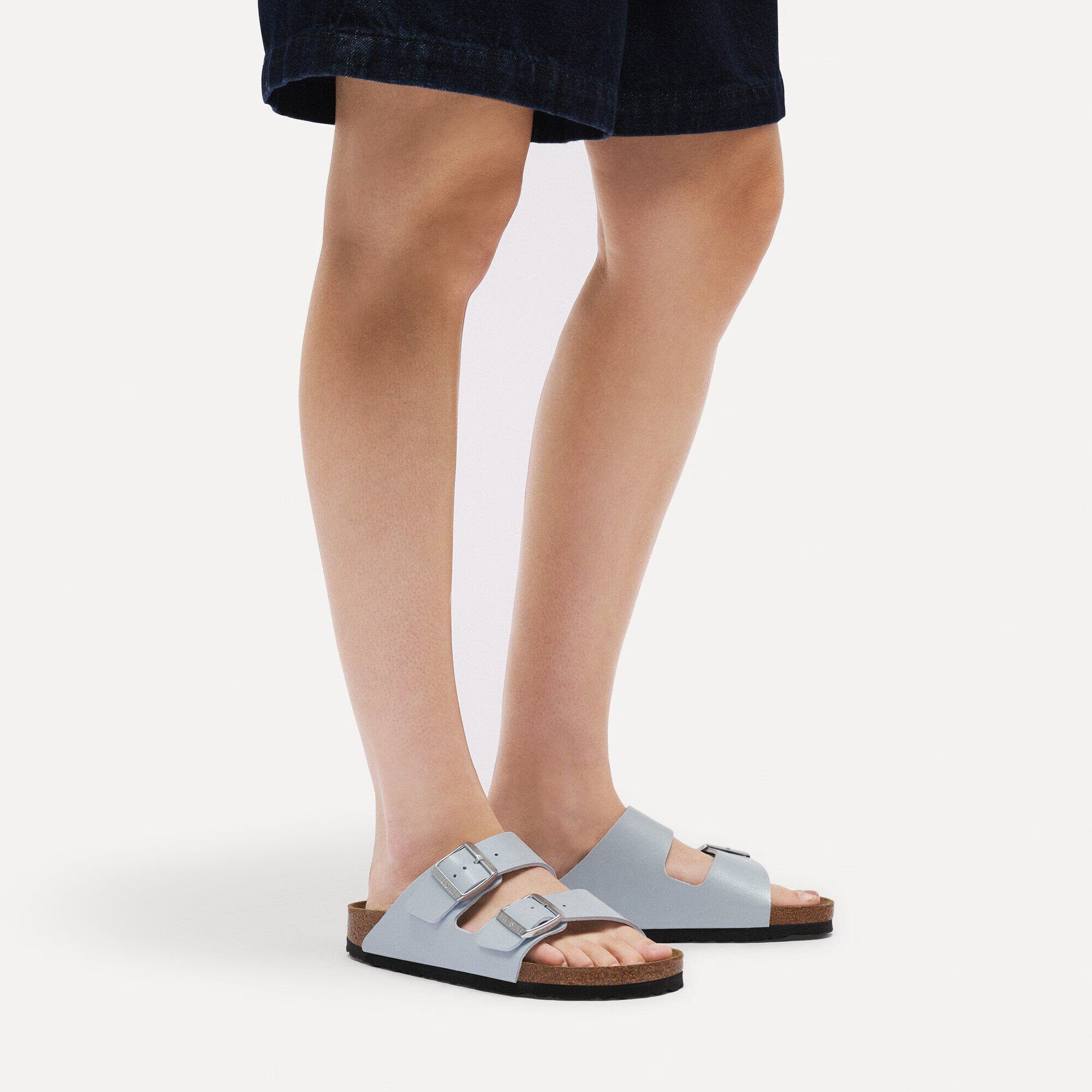 Person wearing light blue sandals on a white background