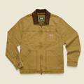 A classic Carhartt like work jacket in a warm tan canvas fabric, featuring a dark brown corduroy collar, a front zipper closure, and a chest pocket with a visible Howler Brothers brand patch.