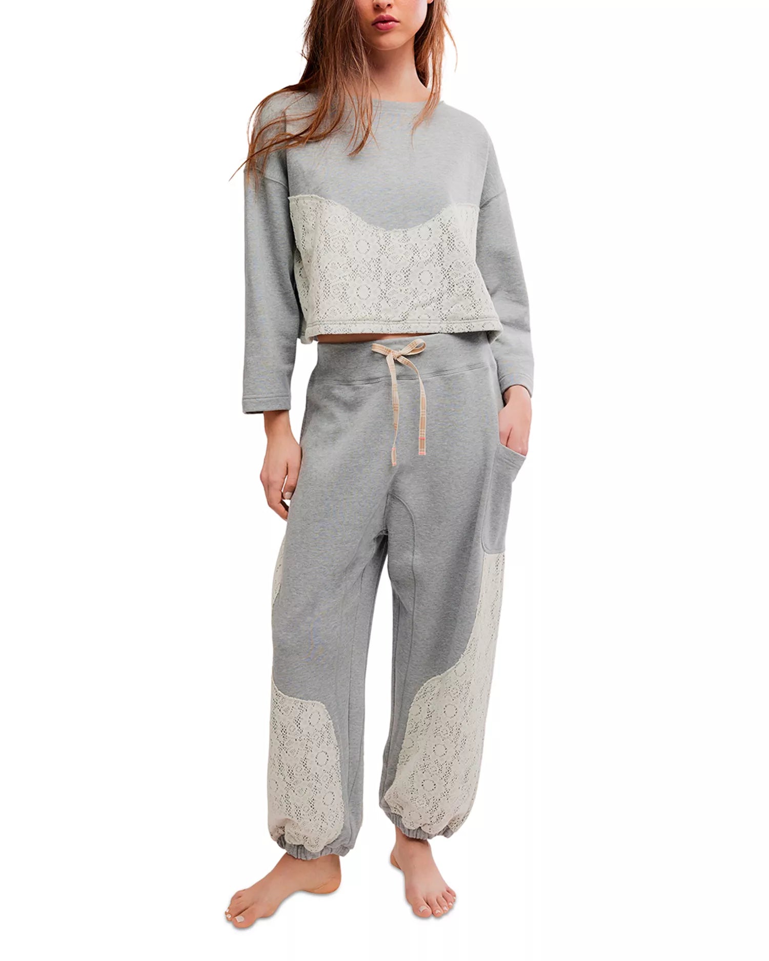 Woman wearing a gray pajama set with lace details on a white background