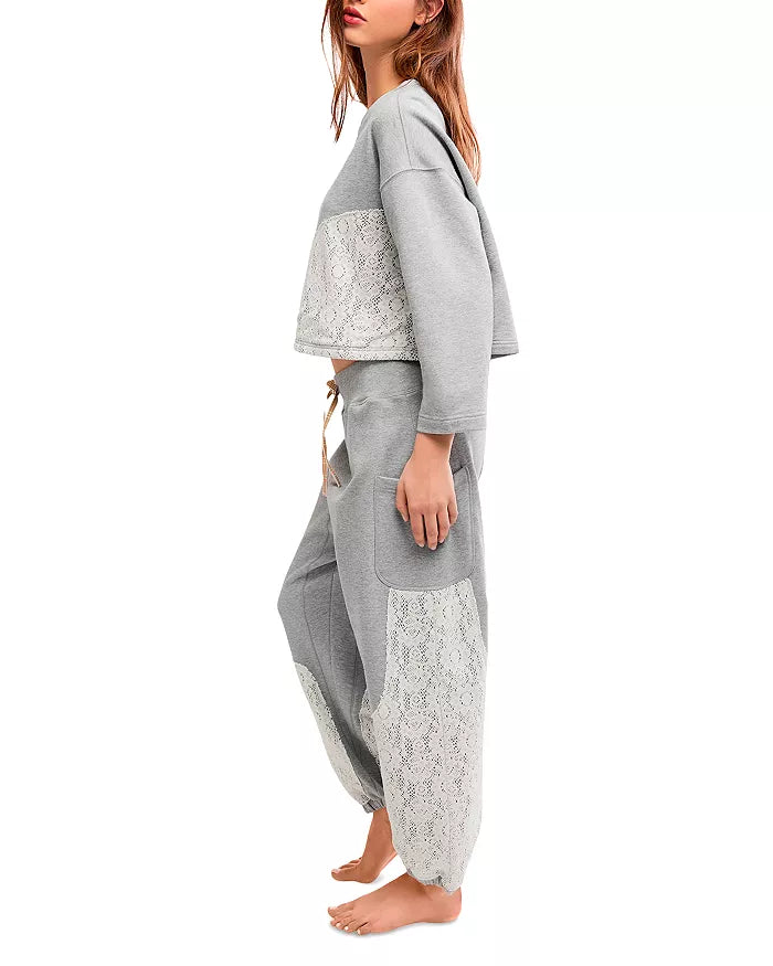 Person wearing a gray outfit with lace details on a white background