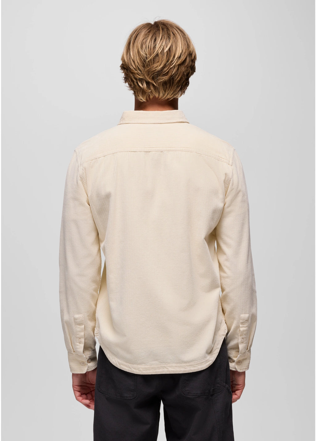 Person wearing a beige shirt with long sleeves on a plain background