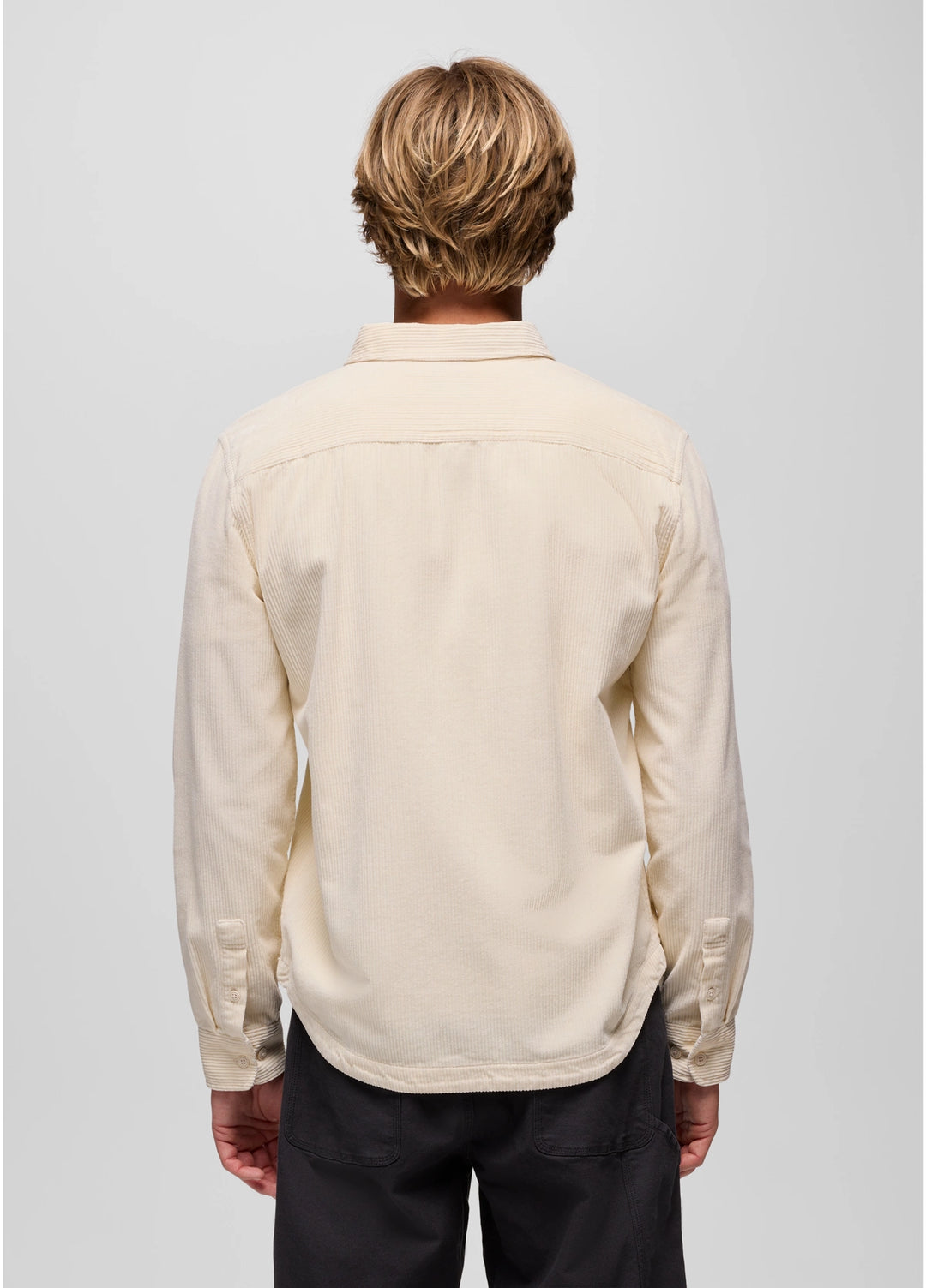Person wearing a beige shirt with long sleeves on a plain background