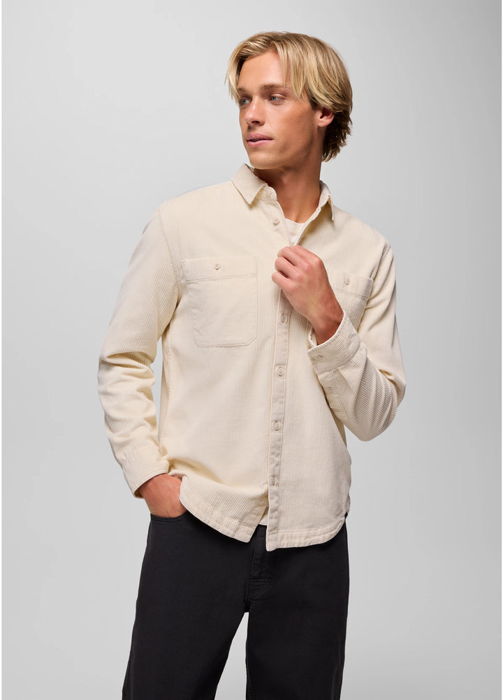 Man wearing a beige shirt and black pants against a gray background