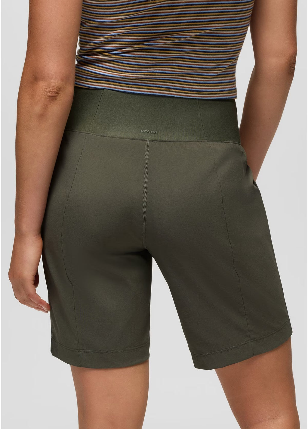 Person wearing green shorts and a striped top on a plain background