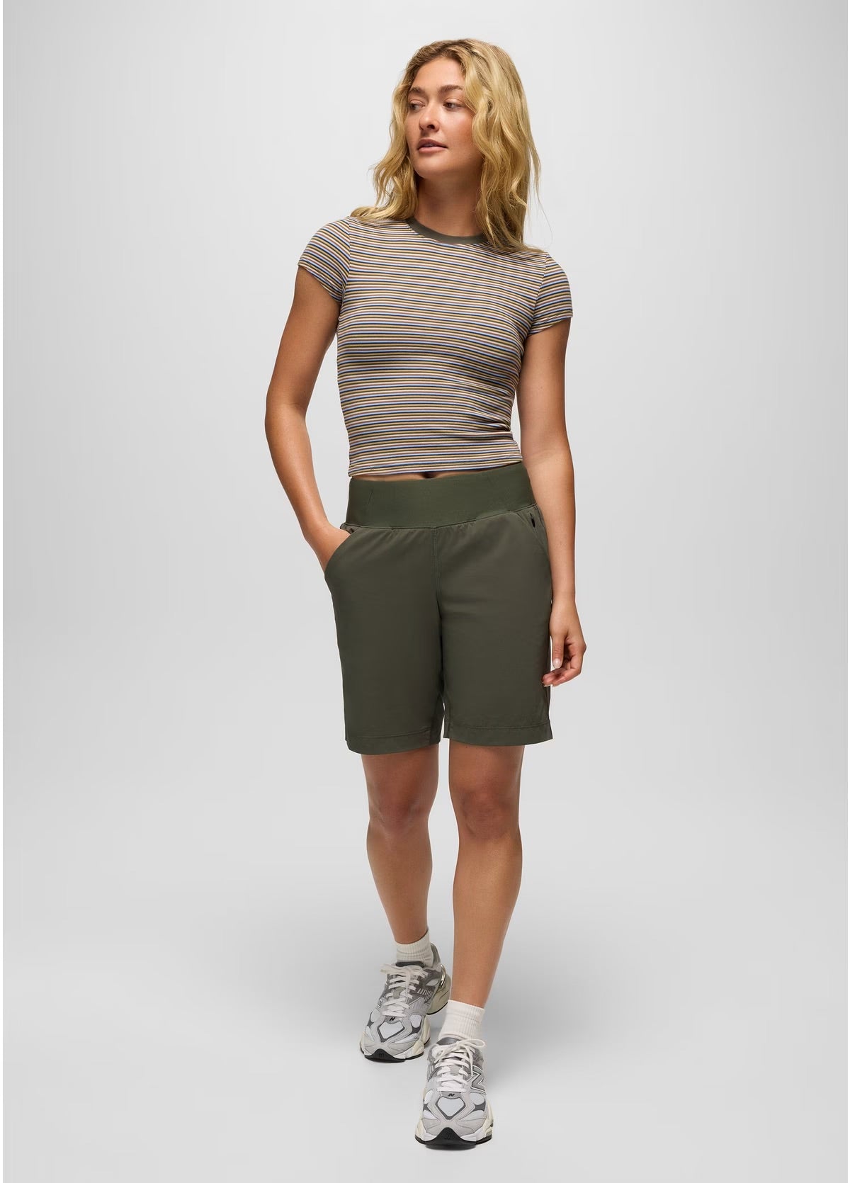 Woman wearing a striped shirt and green shorts on a white background