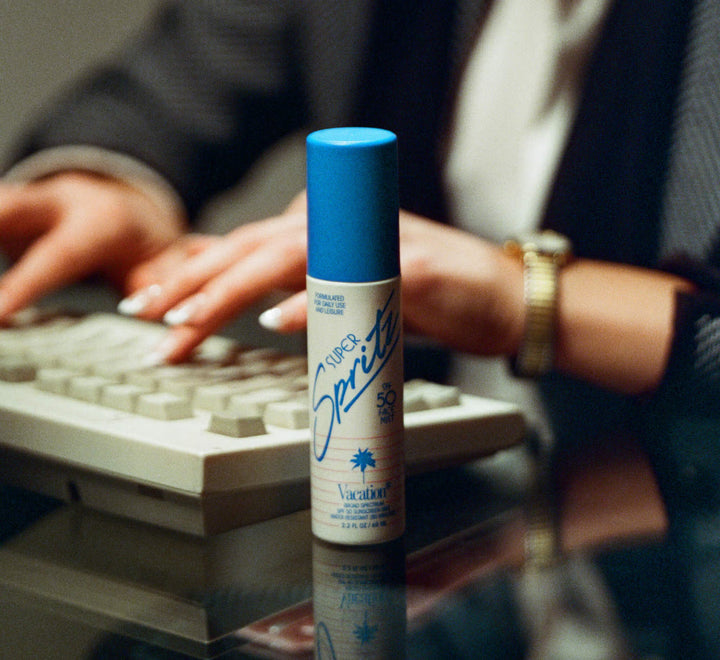 Super Spritz bottle on a desk with a person using a keyboard in the background