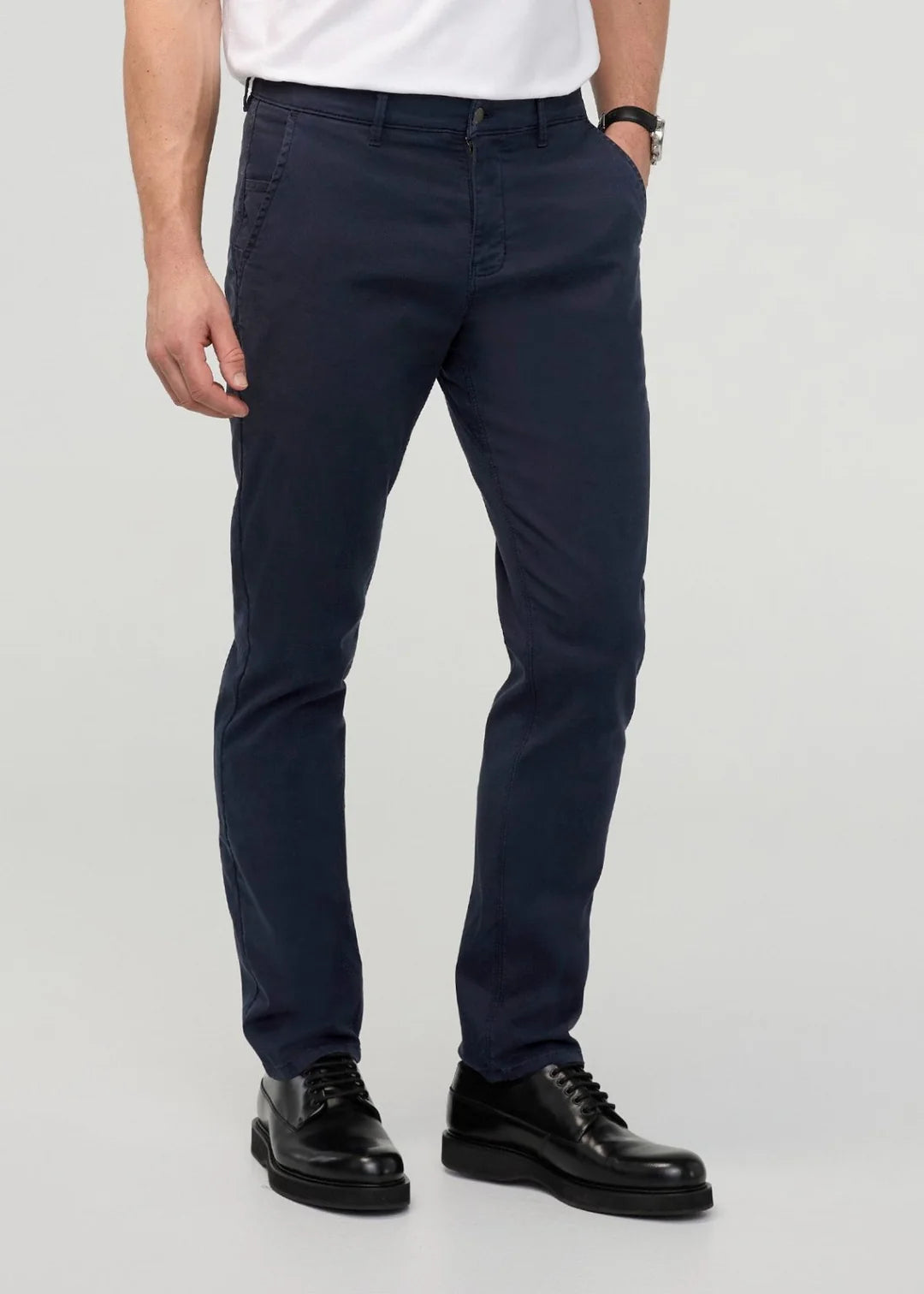 Person wearing navy pants and black shoes on a light gray background