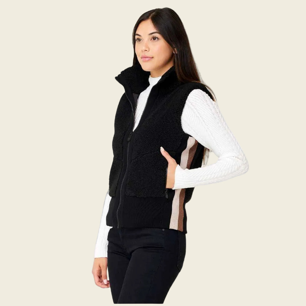 Woman wearing a black vest over a white long-sleeve shirt on a white background