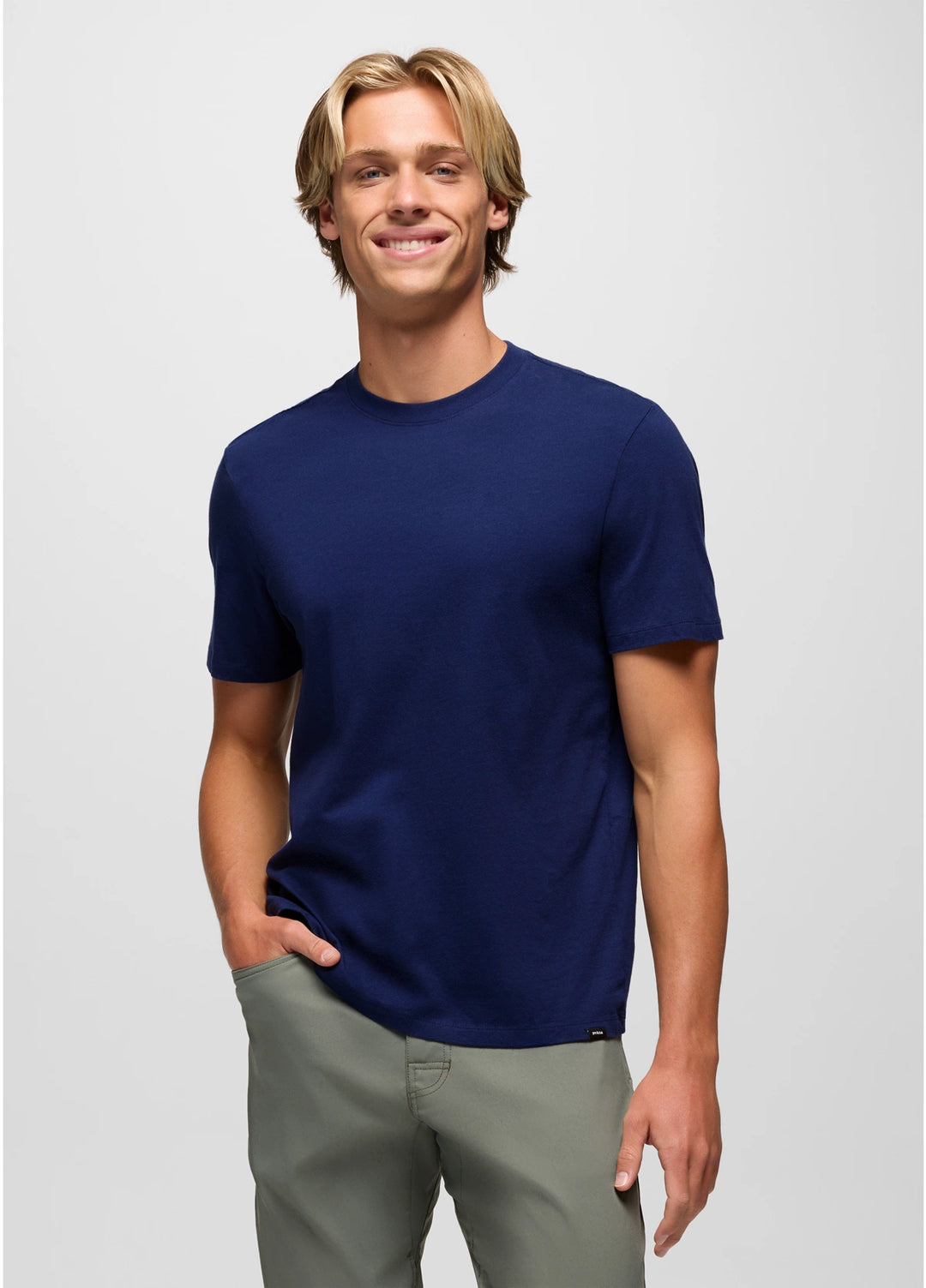 Man wearing a navy blue t-shirt and gray pants on a light gray background