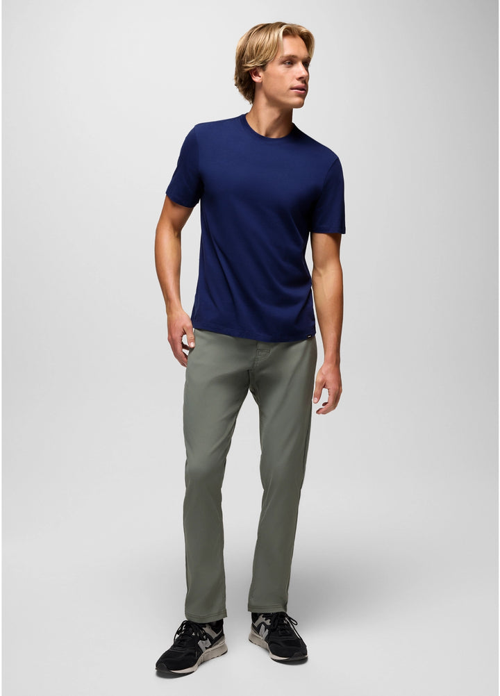 Man wearing a navy blue t-shirt and gray pants on a white background