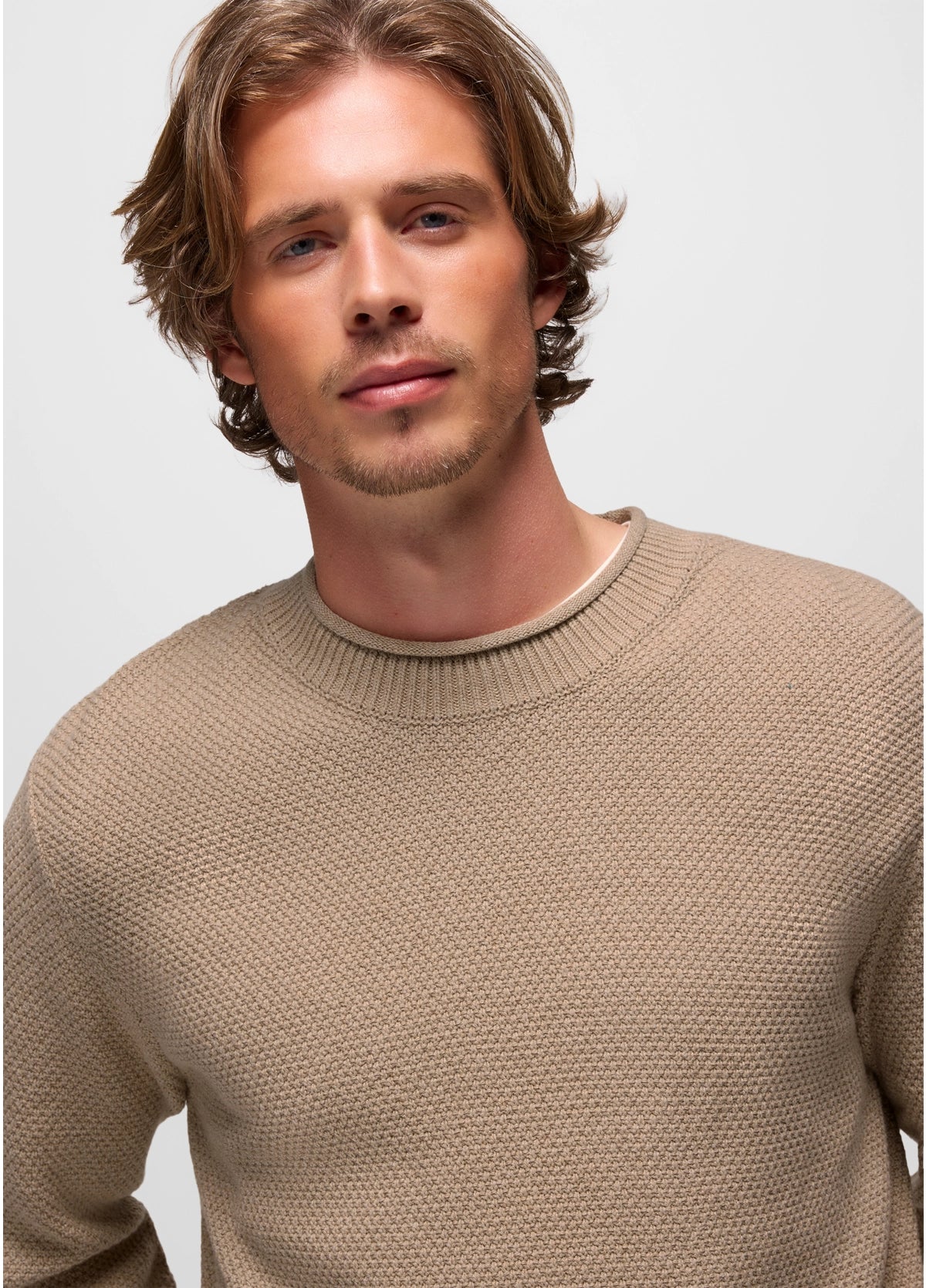 Man wearing a beige sweater against a plain background