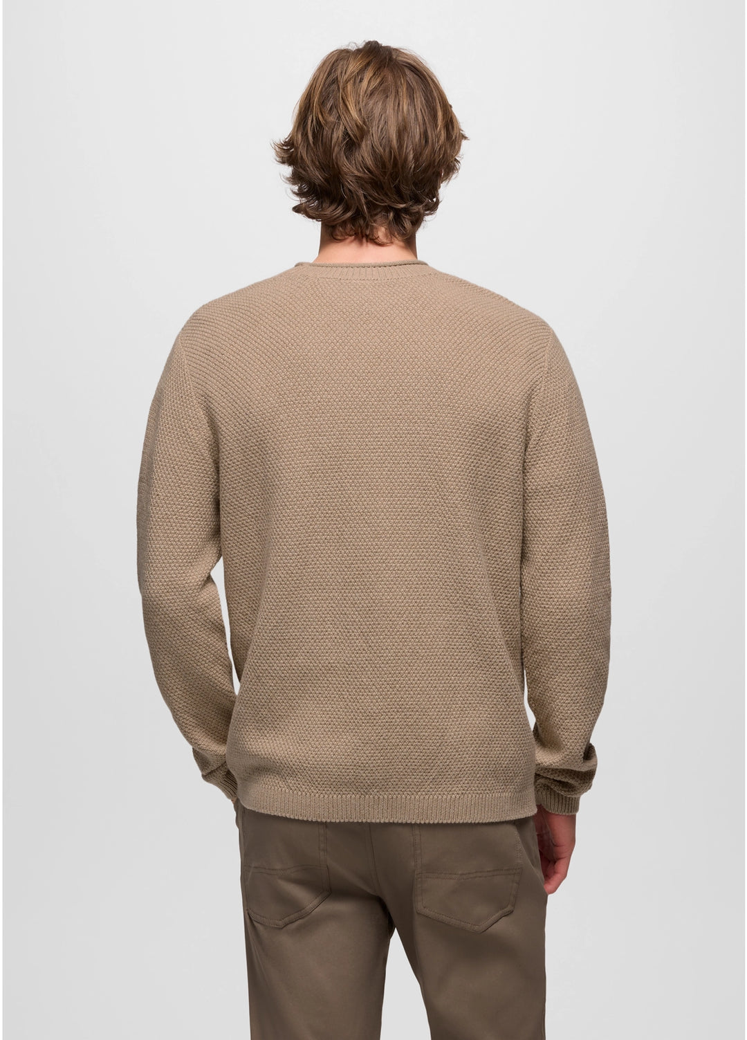 Man wearing a beige textured sweater and pants on a light gray background