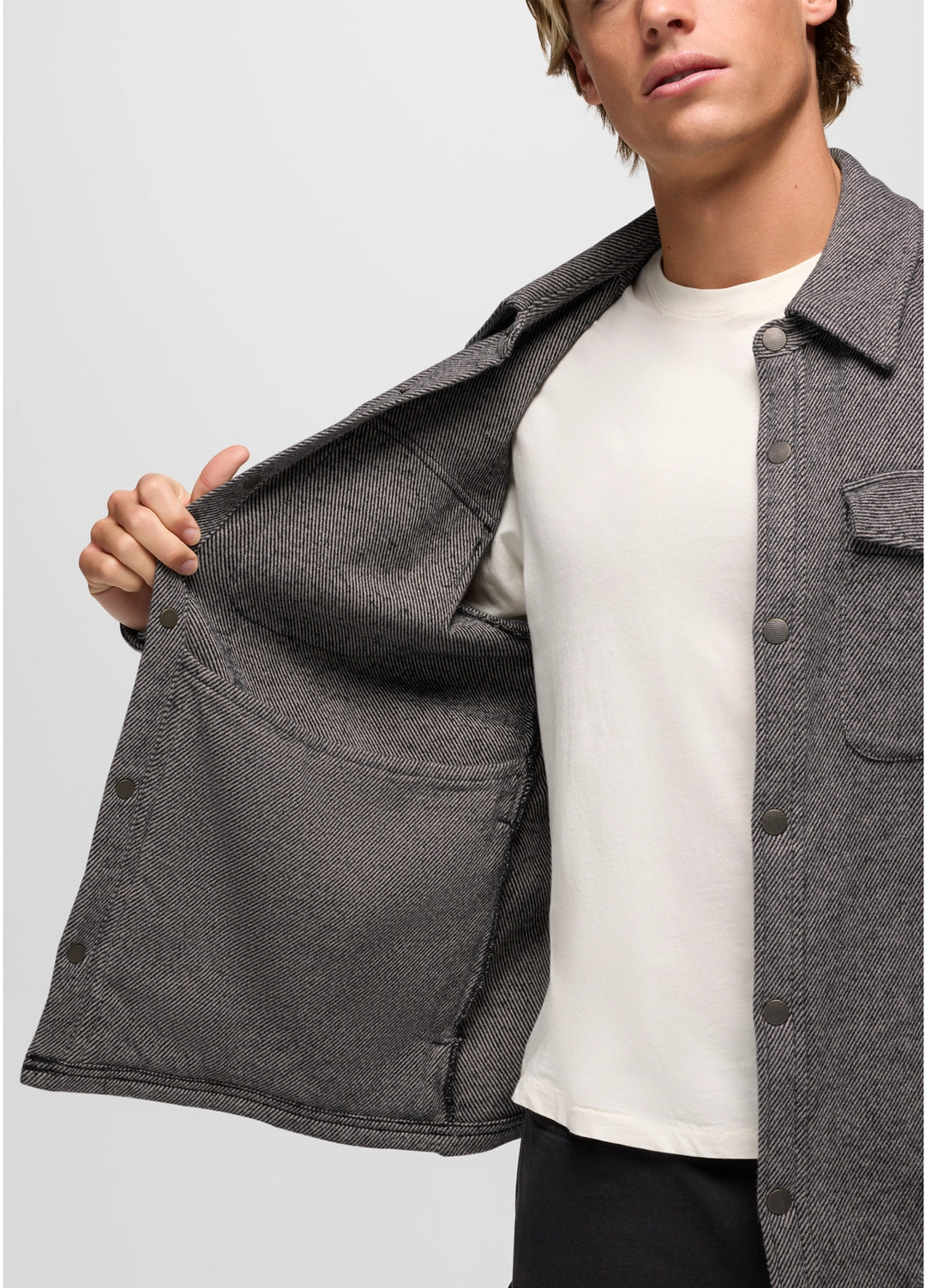 Person wearing a gray jacket over a white shirt on a light gray background