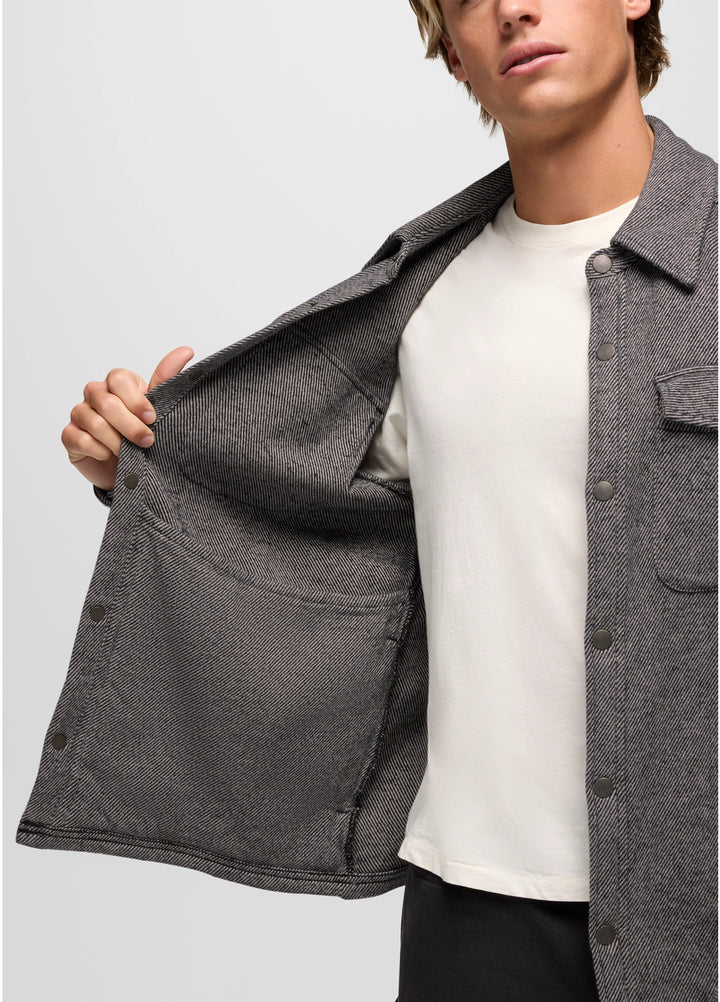Person wearing a gray jacket over a white shirt on a light gray background