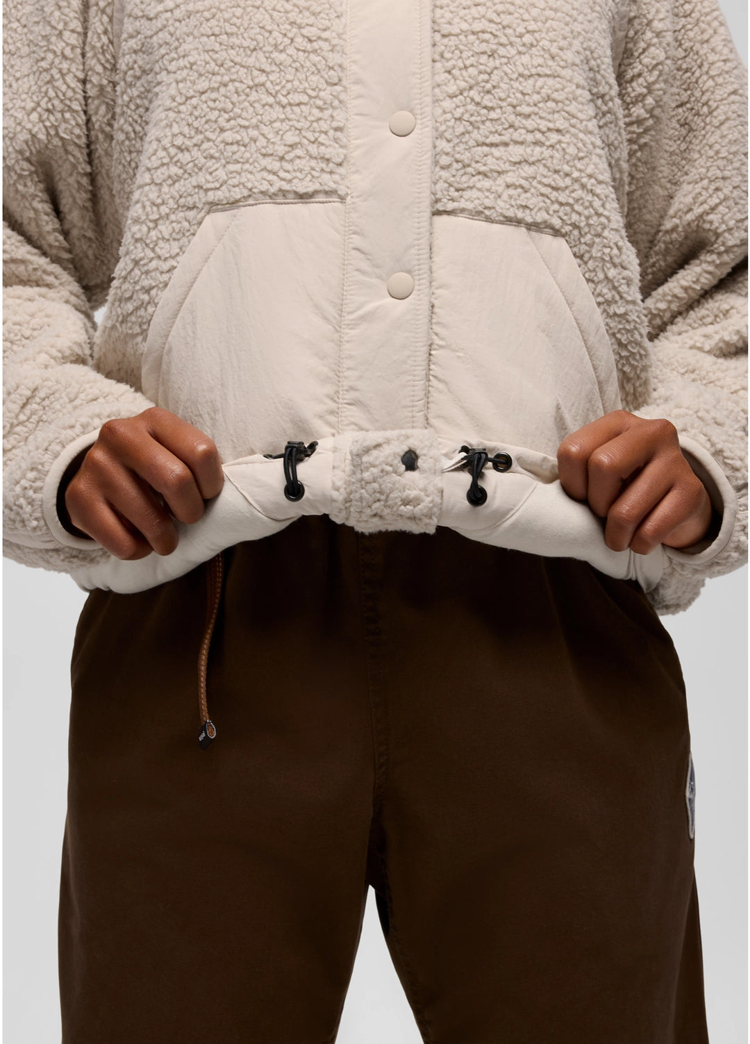 Close-up of a person wearing a beige prAna Encinitas Fleece Jacket with a white quilted panel.