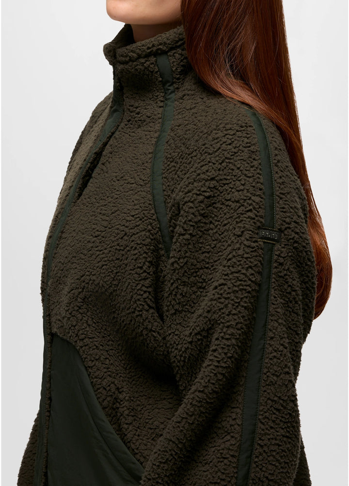 Person wearing a dark green fleece jacket with black accents on a white background