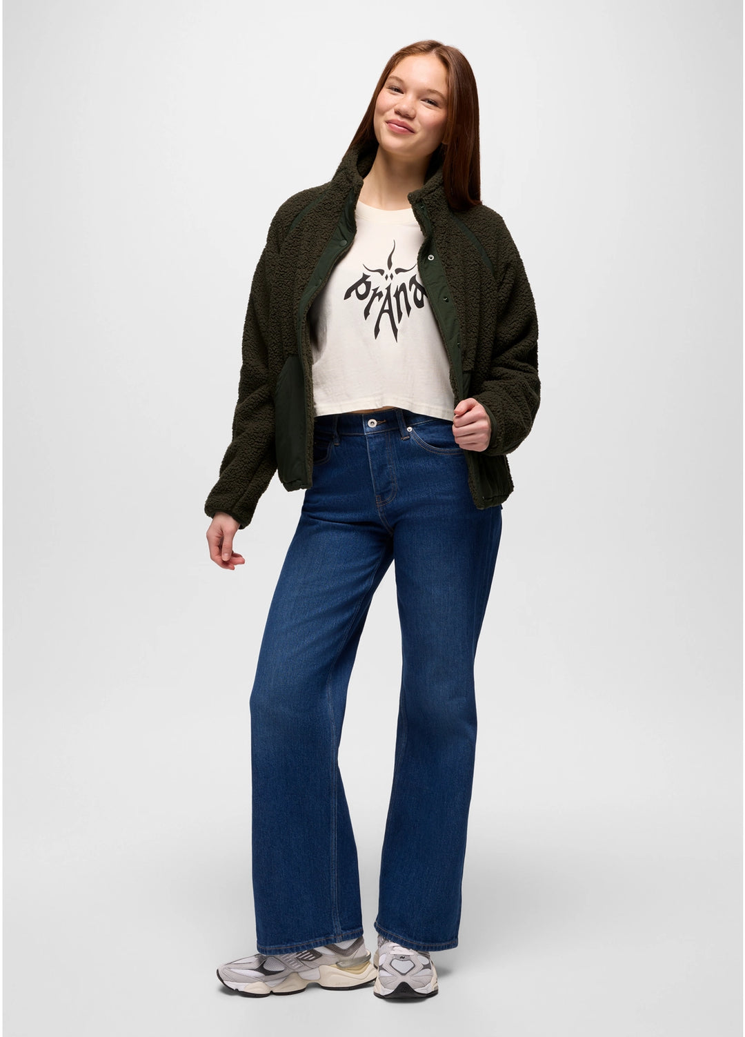 Person wearing a green prAna Encinitas Fleece Jacket, white t-shirt with text, and blue jeans on a white background