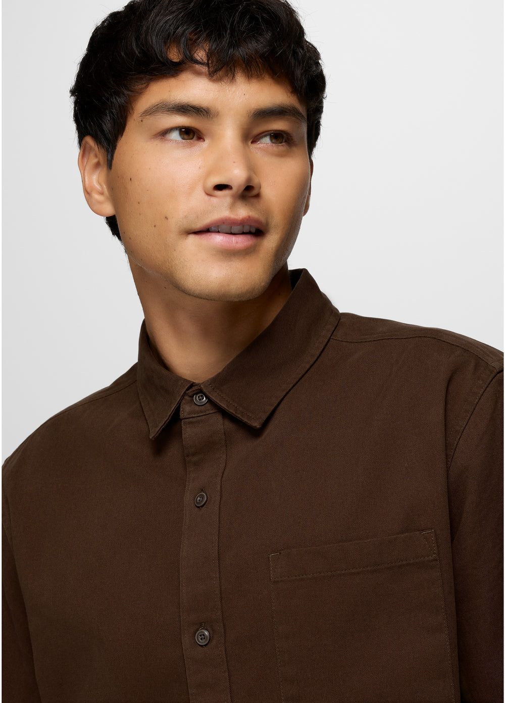 Man wearing a brown shirt against a plain background