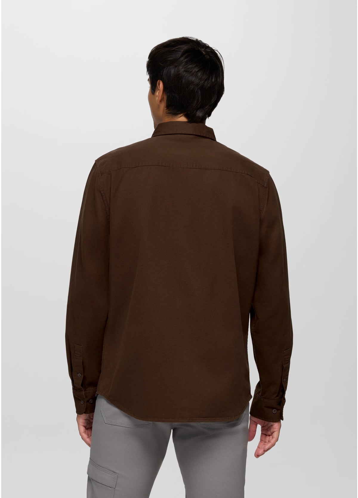 Man wearing a brown shirt and gray pants on a white background