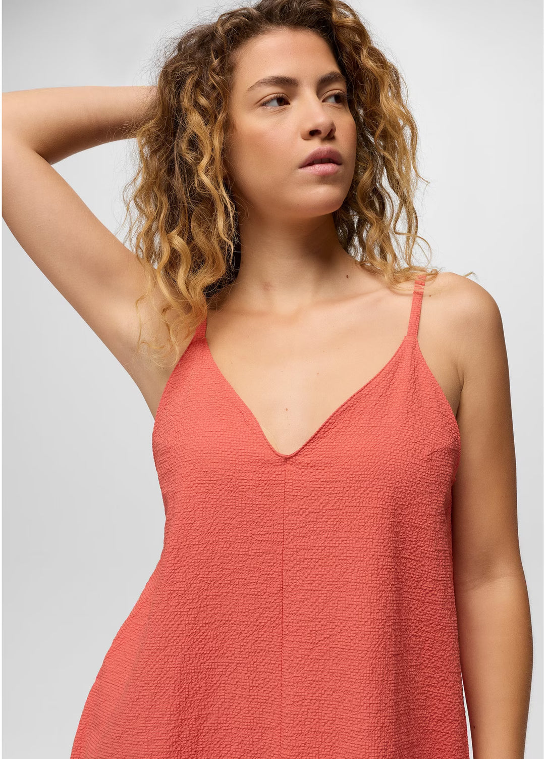 Woman wearing a coral pink dress against a plain background