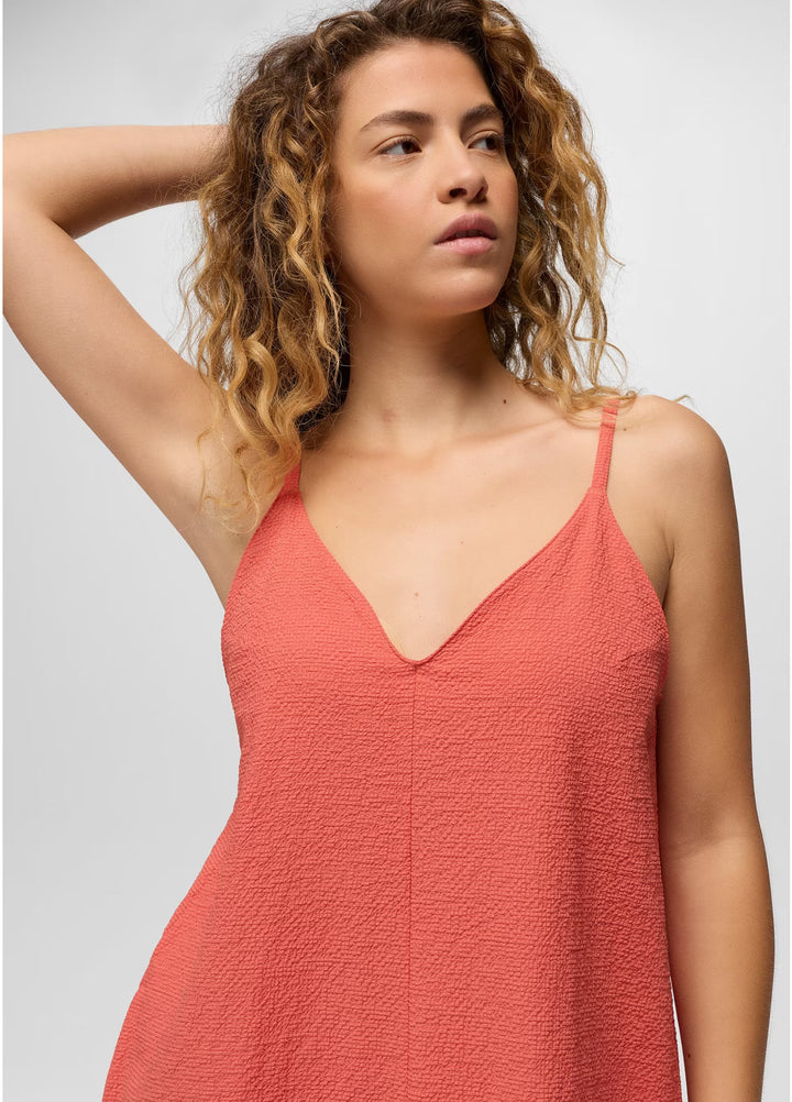 Woman wearing a coral pink dress against a plain background