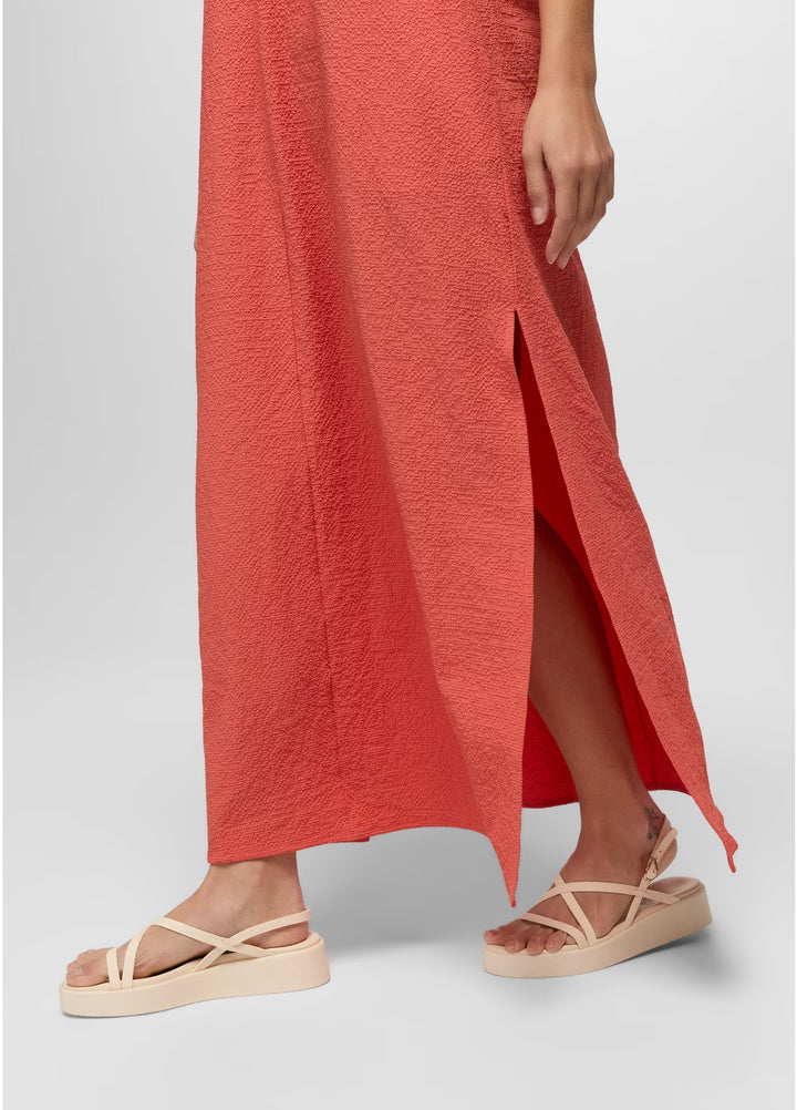 Person wearing a red dress and beige sandals on a light gray background