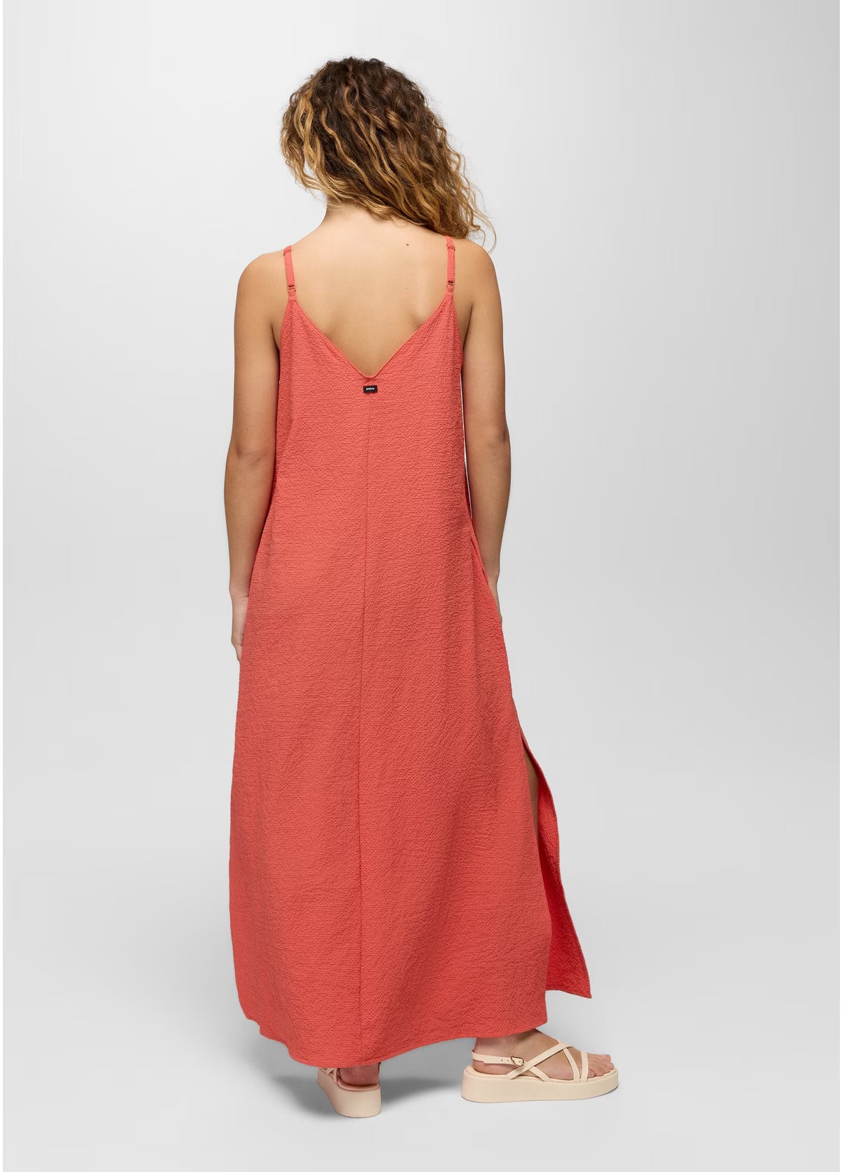 Woman wearing a long coral dress on a white background