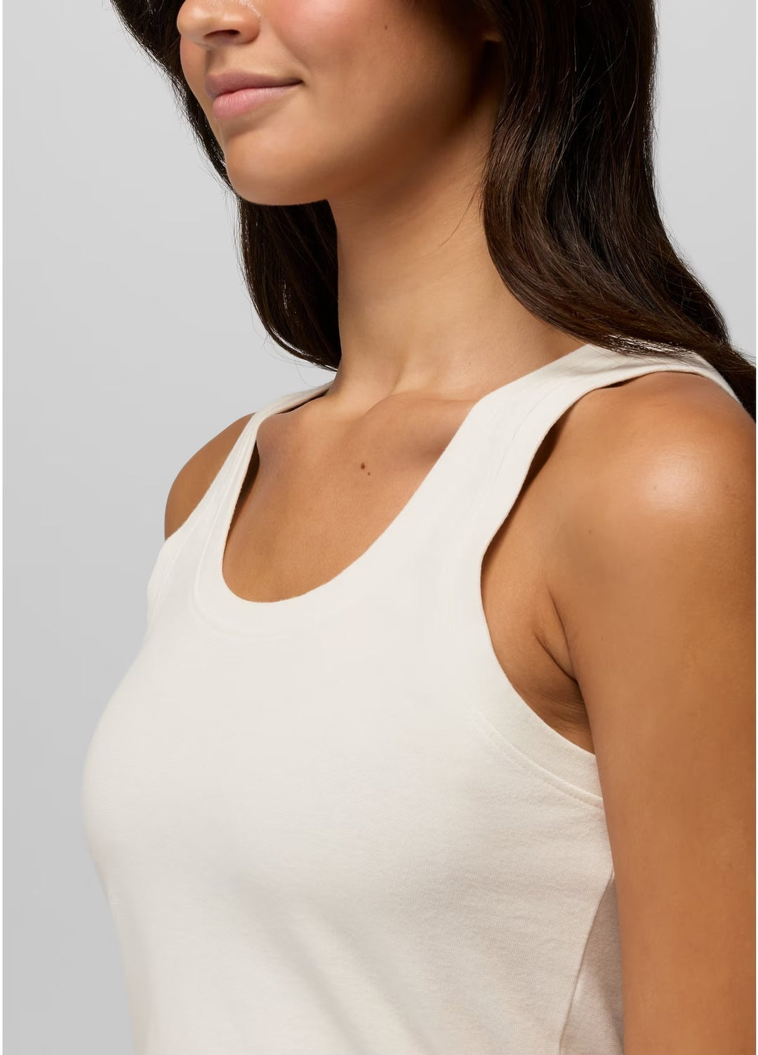Woman wearing a beige tank top against a light gray background