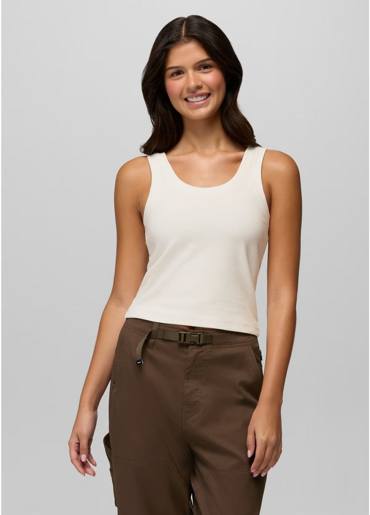 Woman wearing a white tank top and brown pants on a gray background