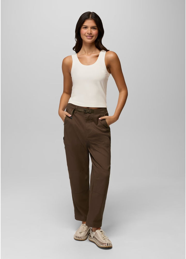Woman wearing a white tank top and brown pants on a gray background