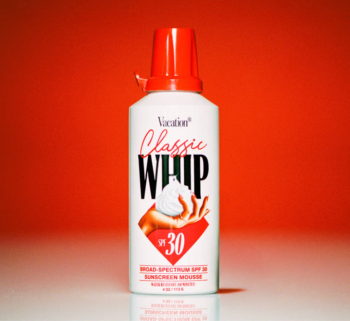 Vacation Classic Whip sunscreen mousse bottle with red cap on a red background