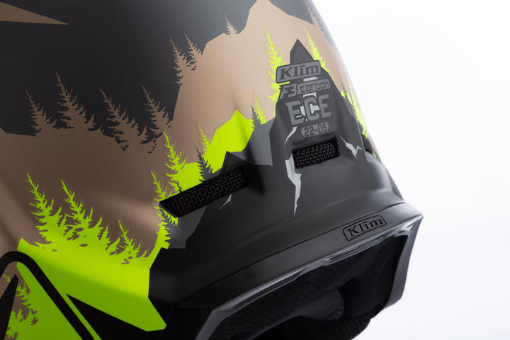 Close-up of a helmet with green and brown design and Klim branding.