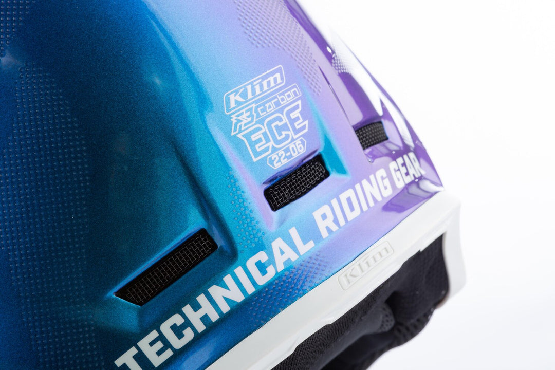 Close-up of a blue and purple helmet with Klim branding on a white background