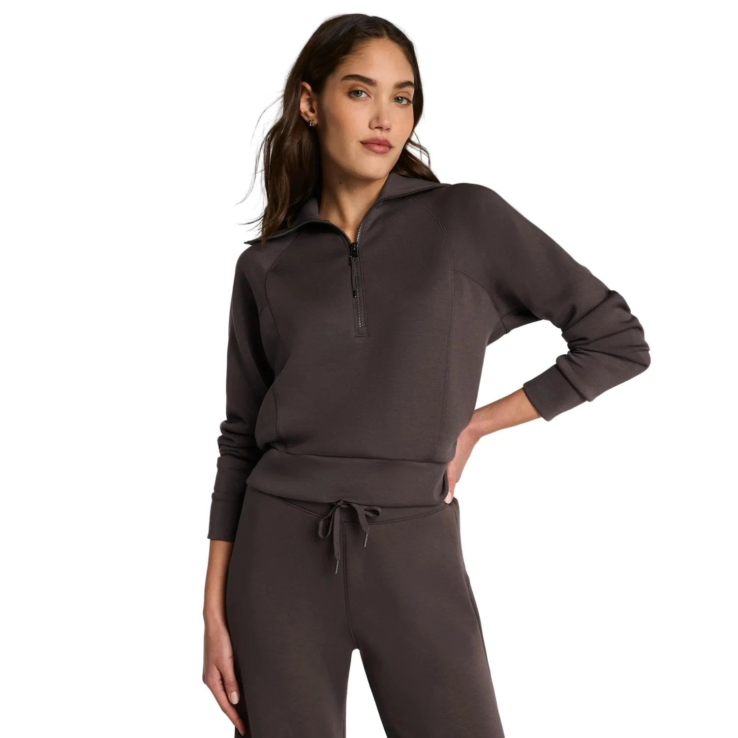 Woman wearing a dark gray hoodie and pants on a white background
